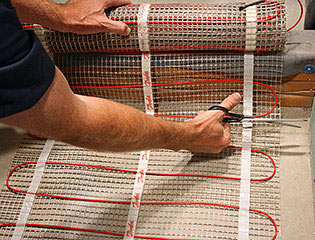Cutting the mesh backing of a floor heating mat to make a turn.